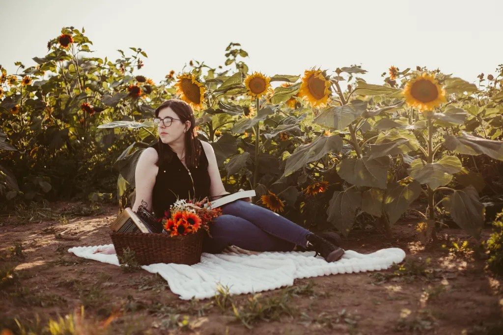 A photo of me sitting on a blanket in a sunflower field. 